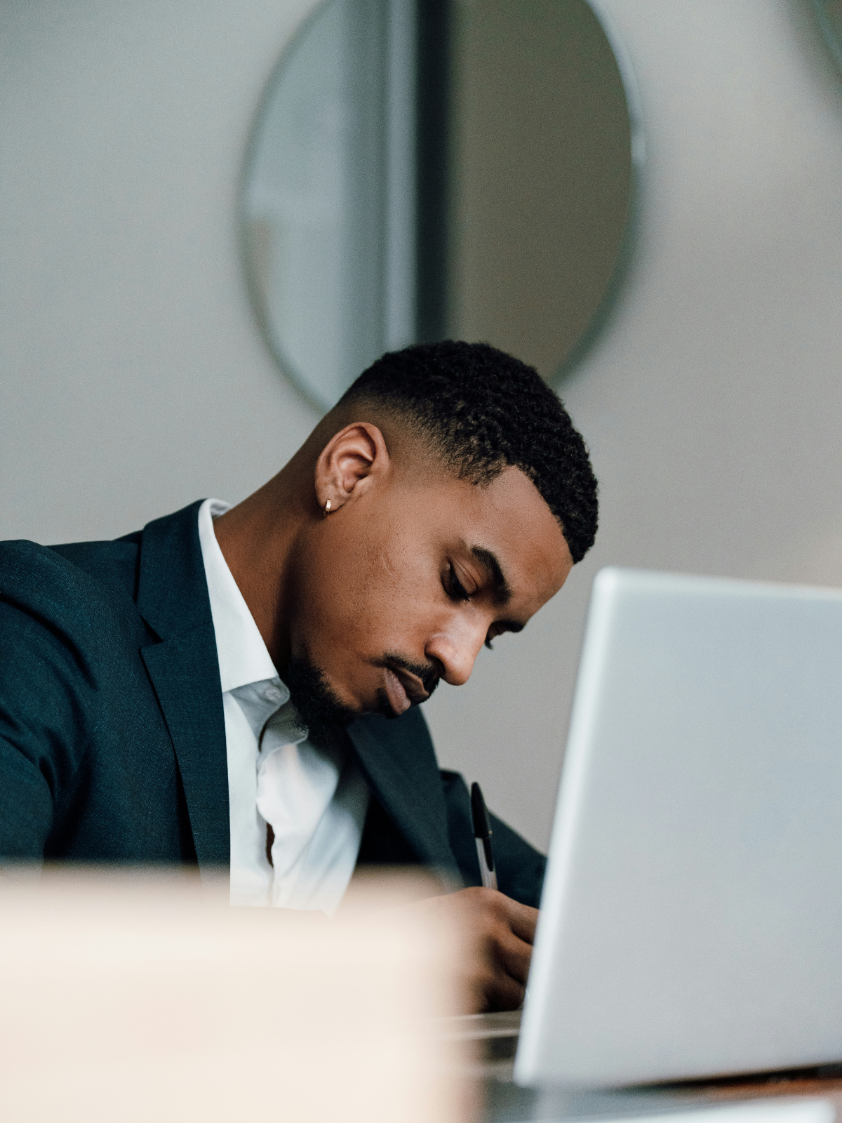 A man writing in a notebook whilst learning from a laptop